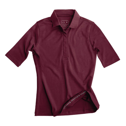 Person wearing a maroon Athlos Polo t-shirt and purple wristband sitting on a red couch.
