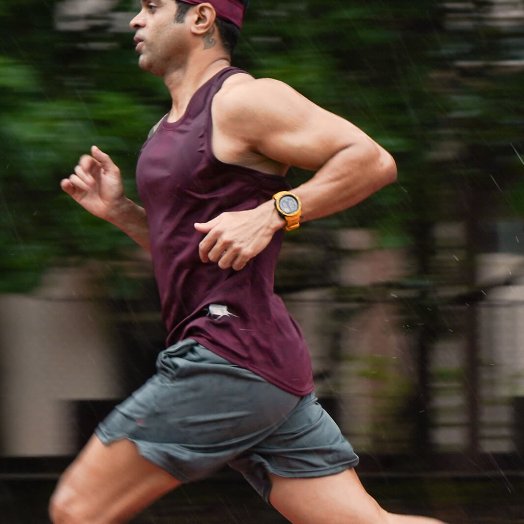 Man running outdoors with a watch on his wrist and wearing Agile Singlet