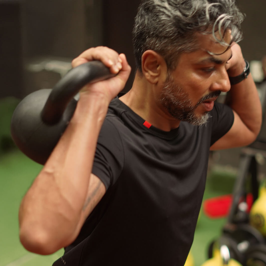 Man lifting a kettlebell in a gym setting wearing Agile tee