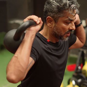 Man lifting a kettlebell in a gym setting wearing Agile tee