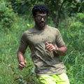 Man running outdoors in a green mens distance tee with sunglasses