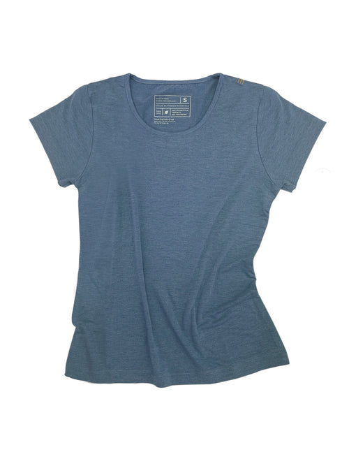 Woman in a gray Athlos Distane t-shirt sitting outdoors with trees in the background