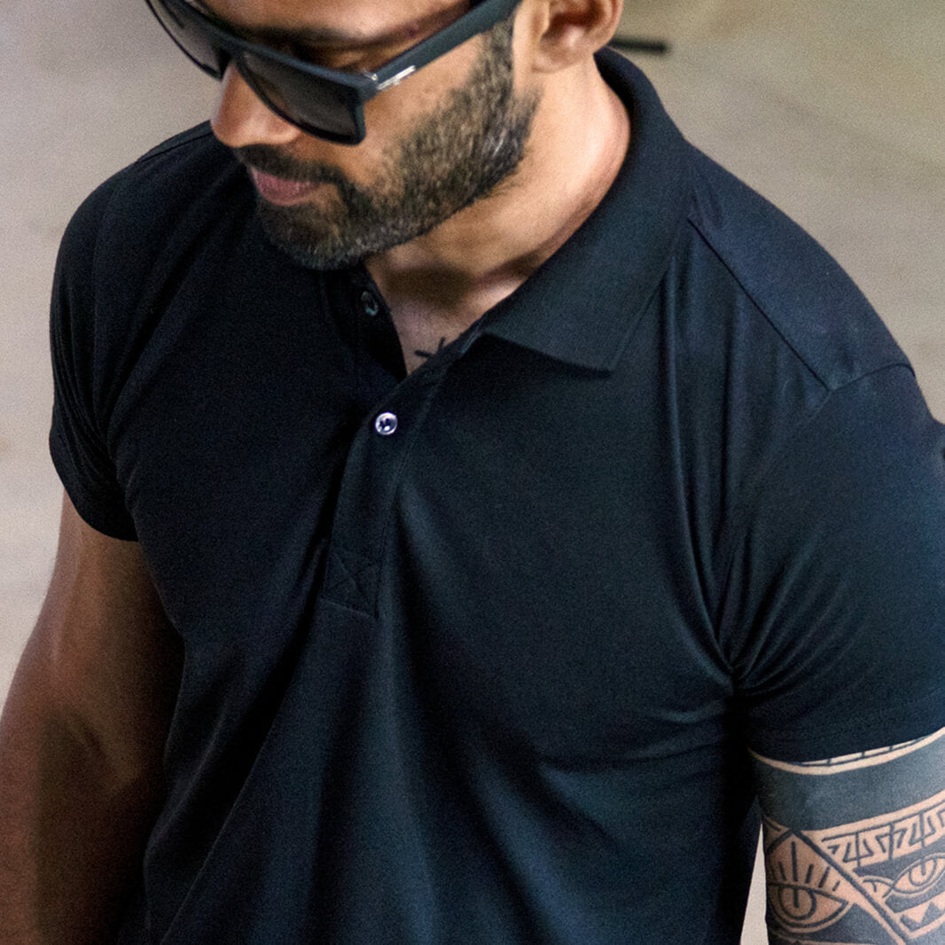 Man wearing a black polo shirt and sunglasses with a blurred background