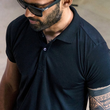 Man wearing a black polo shirt and sunglasses with a blurred background