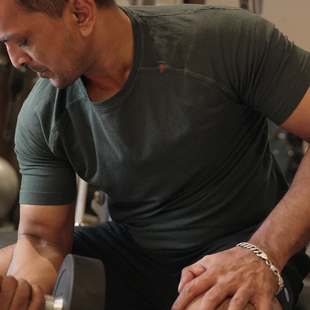 Man in training raglan lifting a dumbbell in a gym setting