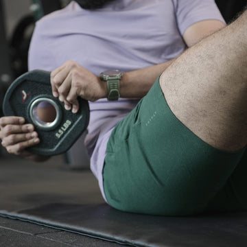 Person holding a weight plate in a gym setting wearing Athlod training Shorts