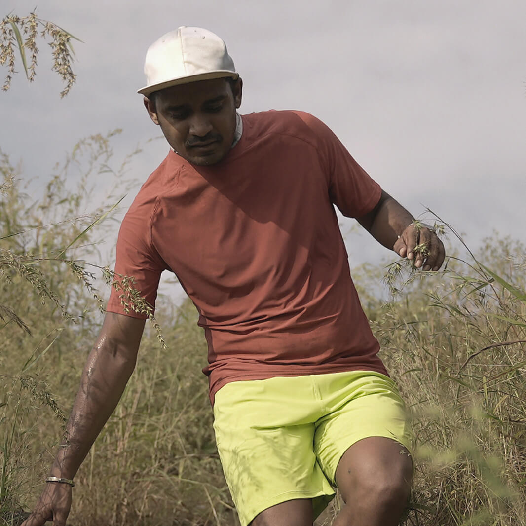 Man in a zero tee walking through tall grass.